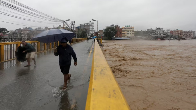 People cross the bridge amid the overflowing Bagmati River following heavy rains, in Kathmandu, Nepal September 28, 2024. Photo: REUTERS
